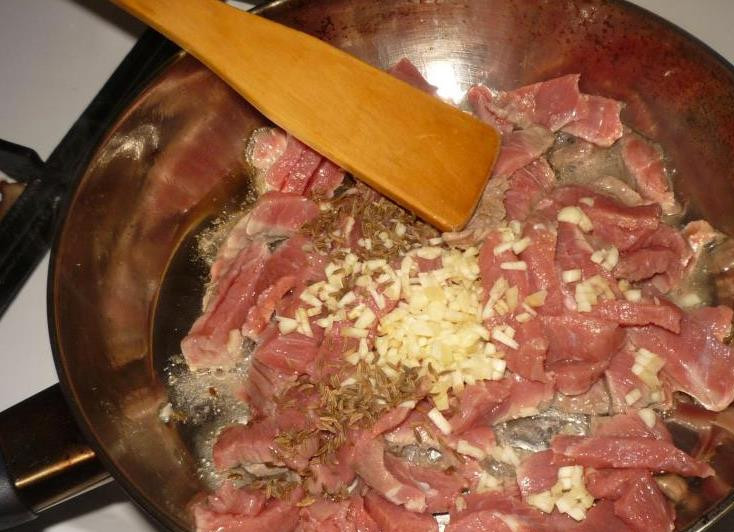 1. Этап. Салат с говядиной и орехами: На раскаленную сковородку наливаем масло. Выкладываем мясо, добавляем мелко нарубленный чеснок и тмин. обжариваем все около 7 минут, постоянно перемешивая. Затем добавляем рубленные орехи и соевый соус. Жарим на среднем огне около 5 минут.