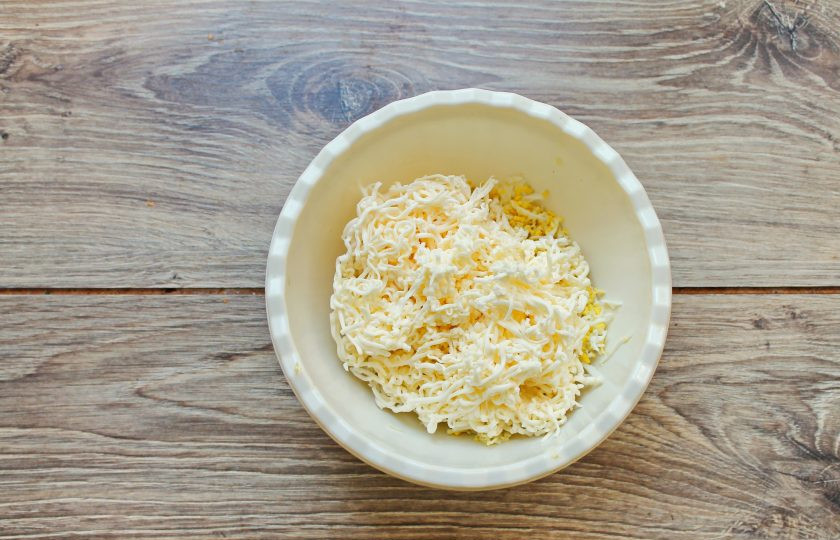 1. Этап. Закусочные конфеты: Плавленый сыр натрите на средней терке и добавьте к яйцам и чесноку.