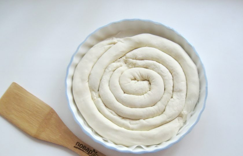 1. Этап. Греческая улитка с сыром и шпинатом: Выложите колбаски из теста с начинкой в форму для выпечки в виде спирали.