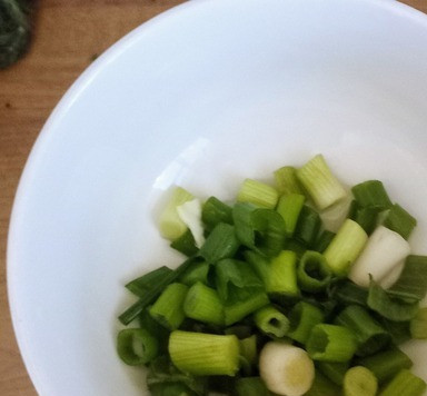 1. Этап. Лапша с арахисовым маслом и кочуджаном: Положить зелёный лук в ёмкость с холодной водой. Дать постоять минуты две. Затем отжать с помощью пальцев, оставив всю грязь на дне ёмкости.