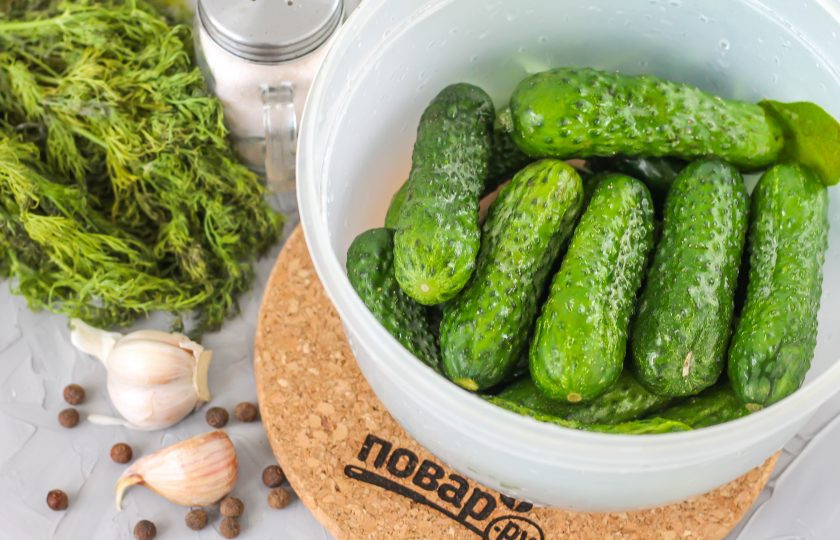 1. Этап. Соленые огурцы по ГОСТу: Промойте свежие огурцы в воде, удаляя шипы и грязь. По желанию можете срезать хвостики у овощей, так они быстрее просолятся, примерно на 1 день. Выложите их в емкость.