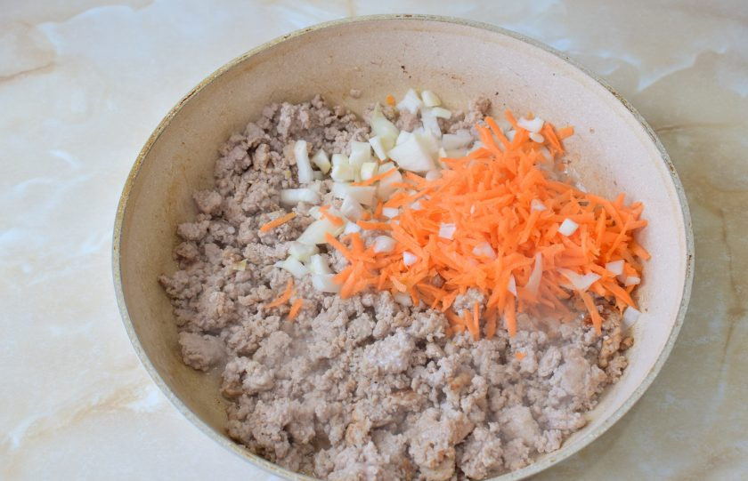 1. Этап. Бабушкины пуховые пирожки: Для приготовления начинки обжарьте 5-7 минут мясной фарш. Затем добавьте к нему измельченные морковь и лук. Обжарьте все вместе еще пару минут.
