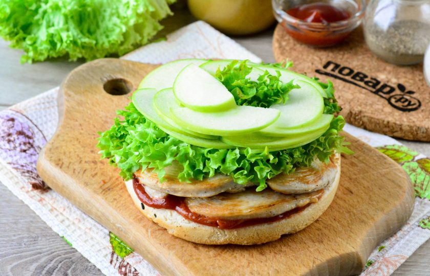 1. Этап. Бургер с курицей, яблоком и сыром: Выложите листья салата и ломтики яблок. Желательно использовать кисло-сладкие яблоки.