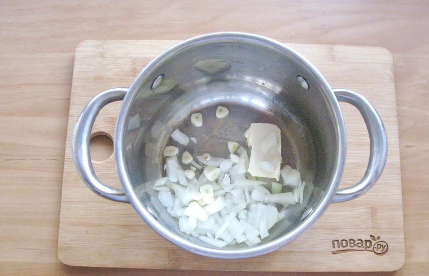 1. Этап. Тыквенный суп с мясом краба: Репчатый лук и чеснок очистите и помойте. Мелко нарежьте и выложите в кастрюлю с толстым дном. Добавьте кусочек сливочного масла.