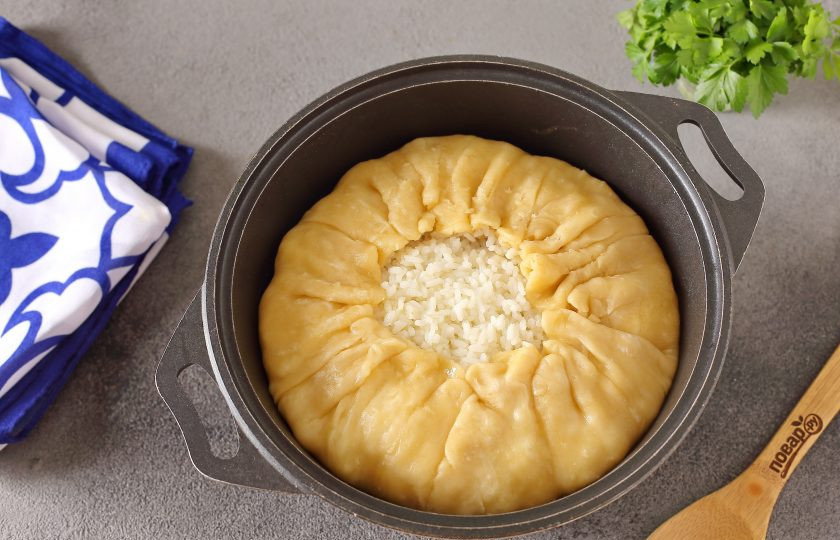 1. Этап. Газмаг для плова: Выложите на мясо оставшийся рис, разровняйте его и снова полейте растопленным сливочным маслом. Тесто для газмага подверните к середине. Готовьте сначала на сильном огне 10 минут, затем на самом маленьком около 1,5 часов.