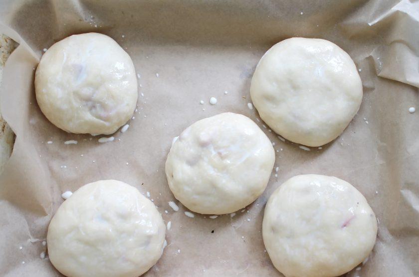 1. Этап. Пирожки с клубникой из дрожжевого теста в духовке: Сформируйте пирожки и выложите их на противень застеленный пергаментом и смазанный растительным маслом. Накройте противень и дайте постоять в теплом месте в течение 10-15 минут для подъема. Смажьте верх пирожков молоком.