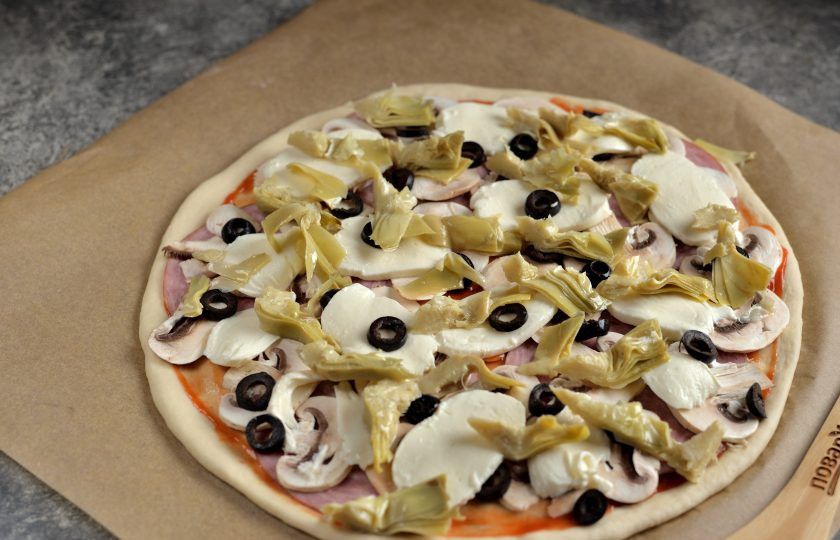 1. Этап. Пицца Каприччио: Теперь нужно тонко нарезать артишоки и разложить их поверх заготовки следующим слоем.