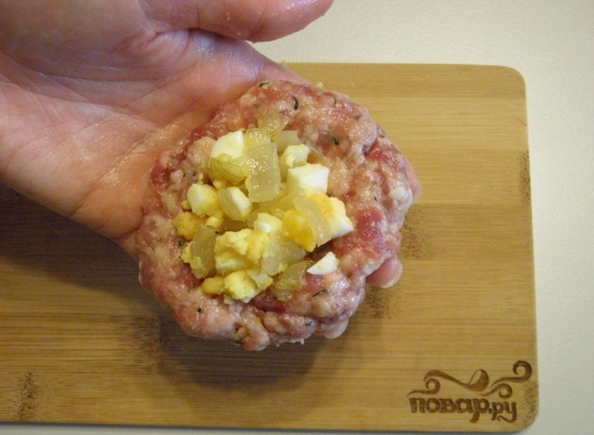 1. Этап. Зразы из фарша в духовке: Возьмите в руку столовую с горкой ложку фарша, сделайте лепешку. В центр положите десертную ложку яичной начинки.