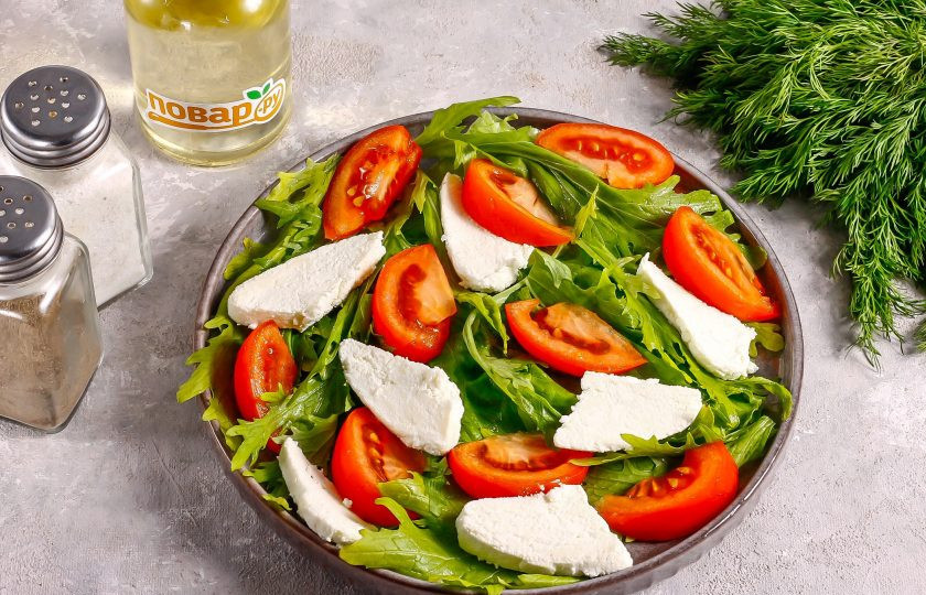 1. Этап. Салат с рукколой и адыгейским сыром: Нарежьте аккуратно адыгейский сыр, чтобы он не разломился на отдельные кусочки. Выложите между нарезки томатов.
