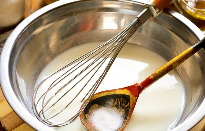 1. Этап. Оладьи на кефире как пух: Всыпьте в кефирную массу пищевую соду, размешайте при помощи венчика. Сода вступит в реакцию и немного зашипит.