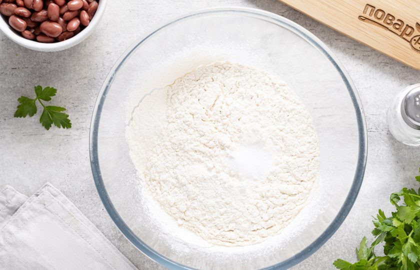 1. Этап. Вареники с фасолью: В глубокой миске смешайте просеянную муку и соль.