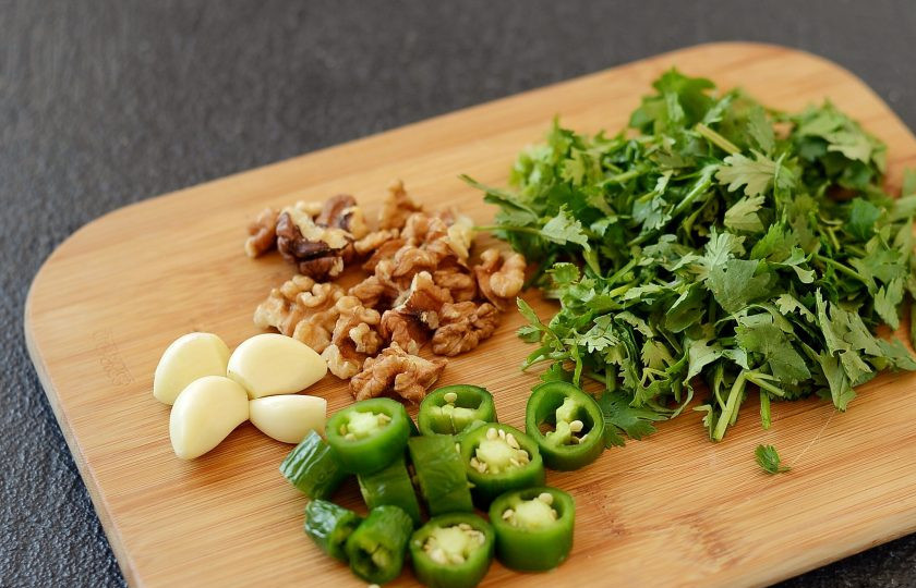 1. Этап. Зеленая аджика по-абхазски: У острого перца отрежьте хвостик, нарежьте кружочками. Грецкие орехи обжарьте на сухой сковороде до раскрытия аромата. Чеснок разделите на зубчики и очистите. Зелень помойте, обсушите и крупно порубите.