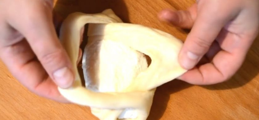 1. Этап. Открытые пирожки с творогом: 6. Вытяните надрезанные края пирожка, проденьте их друг в друга и закрепите с противоположных сторон так, чтобы верх пирожка остался открытым.