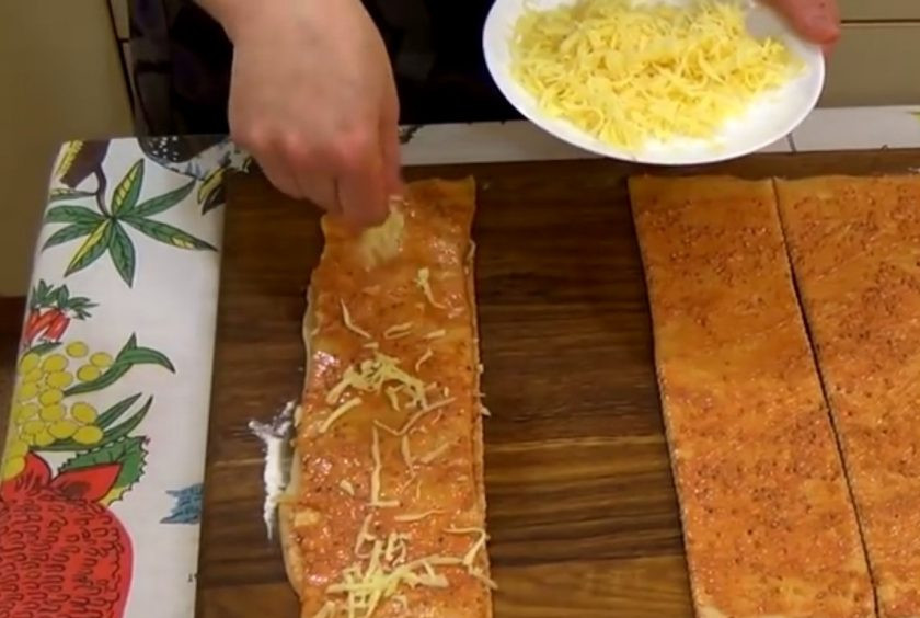 1. Этап. Хлеб Гармошка на пиве с сыром: 4. На первую полосу выложите тертый сыр и прикройте второй полосой. На нее также выложите тертый сыр и прикройте третьей полосой. Повторите со всеми полосами.