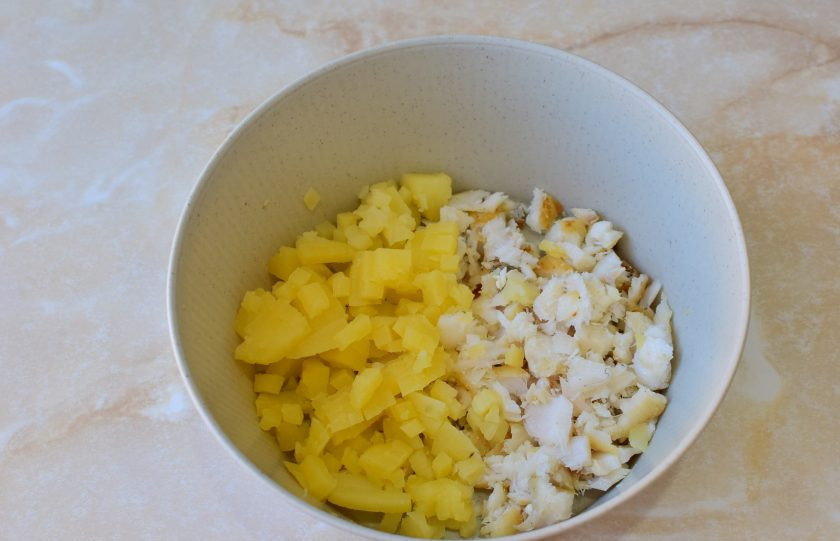 1. Этап. Салат с треской и огурцом: Рыбу и картофель нарежьте небольшими кубиками. Выложите в чашу.
