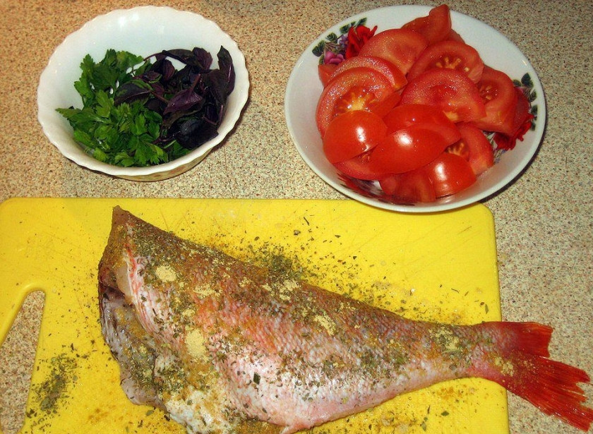 1. Этап. Морской окунь запеченный: Окуня натираем смесью из соли, перца и приправ. Оставляем рыбу на 30 минут. В это время займемся овощами. Лук нарезаем полукольцами, посыпаем солью и поливаем уксусом. Затем маринованный лук обжариваем на сковороде под крышкой в оливковом масле около 10 минут (на небольшом огне). Отставляем в сторону. Картофель, морковь и болгарский перец нужно испечь заранее, так как окунь готовится очень быстро. Помидоры нарезаем тонкими дольками.