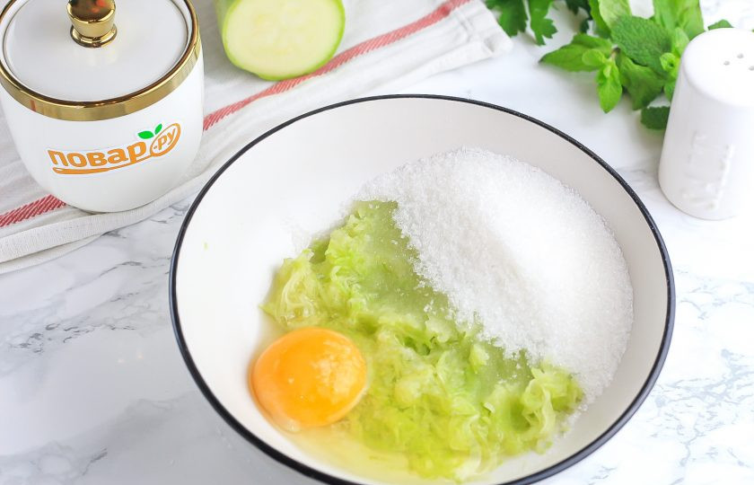 1. Этап. Печенье из кабачков с овсяными хлопьями: Промойте кабачок в воде и отрежьте половину. Натрите ее в глубокую емкость и посолите, оставьте на 5 минут, чтобы выделилась жидкость. Отожмите и вбейте в массу куриное яйцо, всыпьте сахар и взбейте.