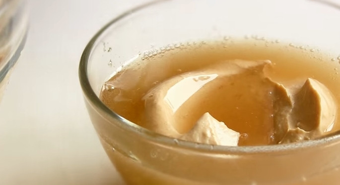 1. Этап. Чизкейк Карамельный по-домашнему со сгущенкой: 6. Растопите желатин в микроволновке, отправьте к нему ложку творожной массы. Перемешайте и верните в миску с творожной смесью.