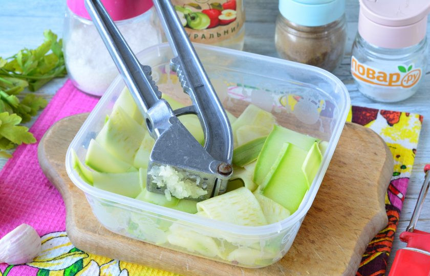 1. Этап. Маринованные кабачки за 30 минут: Выложите кабачки в подходящий контейнер или емкость с крышкой, выдавите чеснок.