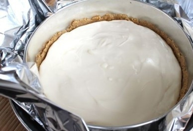 1. Этап. Чизкейк со сливочным сыром: Заворачиваем форму в несколько слоев фольги. Выкладываем сырную массу на основу чизкейка. Ставим форму в посуду большего размера, в которую наливаем воду.