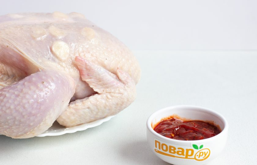 1. Этап. Курица, запеченная с аджикой: Для маринада смешайте кетчуп и аджику. Кусочками чеснока нашпигуйте курицу на грудке под кожей. Натрите всю курицу солью.