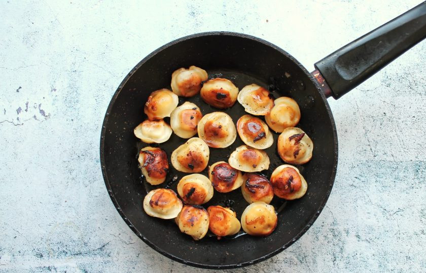 1. Этап. Жареные пельмени с луком на сковороде: Снимите крышку, прибавьте огонь и обжарьте пельмени до румяной корочки с двух сторон.