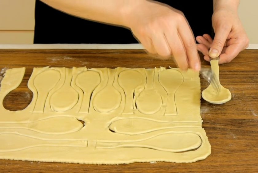 1. Этап. Слоеные ложки с красной икрой: 2. На вогнутую сторону ложки, смазанную сливочным маслом и присыпанную мукой, выложите заготовку из теста так, чтобы она слегка выходила за края. Наколите ложки вилкой.