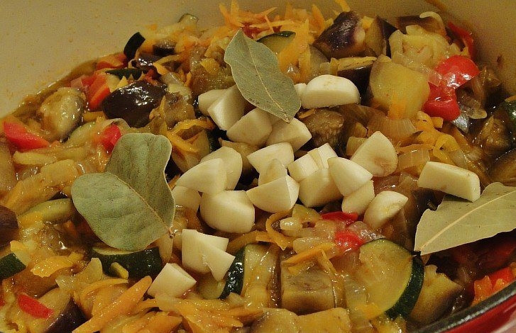 1. Этап. Икра из баклажанов и кабачков: Да, не забываем добавить масло. Тушить овощи следует в течение часа. Через минут 20-30 после начала тушения, открываем крышку, добавляем соль и перец. Содержимое кастрюли должно существенно обмякнуть и осесть. Еще через минут 20 добавляем чеснок и лавровый лист и еще немного тушим содержимое, затем снимаем с огня.