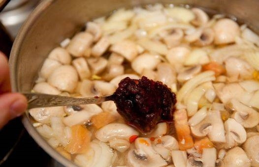 1. Этап. Суп Том ям с креветками: 2. Чистим и моем шампиньоны, срезаем край плодоножки, нарезаем небольшими кусочками. Отправляем их в кастрюлю. Моем и нарезаем лук, помидоры, кладем их в кастрюлю, добавляем пасту чили. Варим все 10 минут.