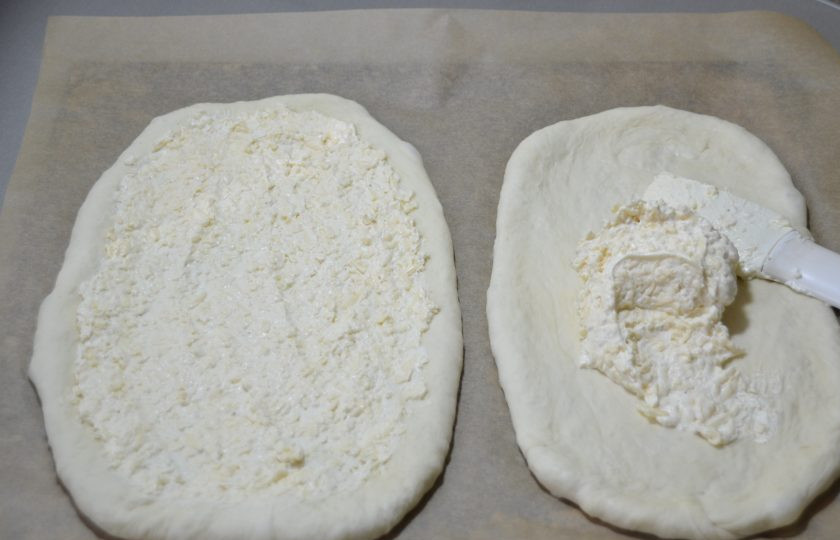 1. Этап. Пицца по-немецки: Нанесите на тесто сливочный крем-соус и разровняйте по всей поверхности ровным слоем.