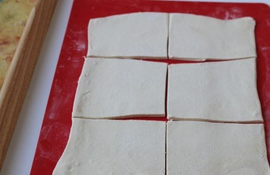 1. Этап. Слойки с вареньем: Достаем из морозилки готовое слоеное тесто и размораживаем его при комнатной температуре. Затем раскатываем его в пласт, толщиной 2-3 мм. Чтобы тесто не прилипало к столу и скалке - подсыпайте муку. Разрезаем тесто на прямоугольники.