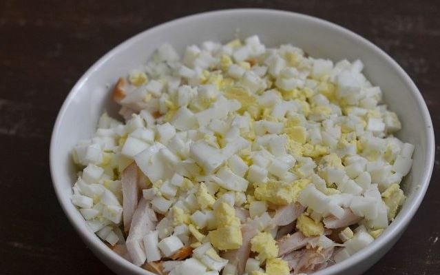 1. Этап. Салат с грудкой и грибами: В небольшую кастрюльку налейте воду и положите в нее сырые куриные яйца. Доведите воду до кипения на плите, отваривайте яйца вкрутую. Затем остудите их и очистите от скорлупы. Нарежьте кубиками и добавьте в салат.