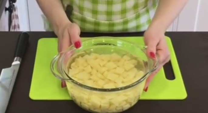 1. Этап. Очень вкусный гороховый суп с копчеными ребрышками: 3. Картошку порежьте кубиками и залейте водой. Лук нарежьте крупными кубиками, морковку — половинками кружочков.