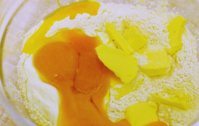 1. Этап. Крендельки с корицей: В глубокую миску просейте муку. Сделайте небольшое углубление. Кусочки холодного масла, сметану, яичные желтки и цедру лимона выложите в муку. Аккуратно перемешайте.