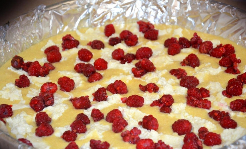 1. Этап. Манник с творогом в духовке: 6. Форму для выпечки застилаю пергаментом или фольгой, выливаю приготовленное тесто. Творог перетираю и выкладываю его поверх теста, мою ягоды малины (свежие или предварительно размороженные) и выкладываю в форму.