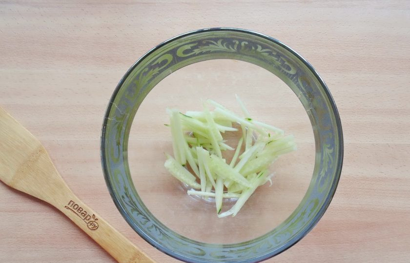 1. Этап. Итальянский салат с фунчозой: Огурец помойте и очистите. Нарежьте тонкой соломкой и выложите в салатник.