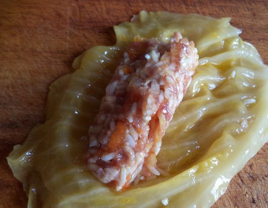 1. Этап. Голубцы из квашеной капусты: 4. Берем капустный лист и выкладываем на него фарш. Заворачиваем конвертом и складываем голубцы в емкость для тушения.