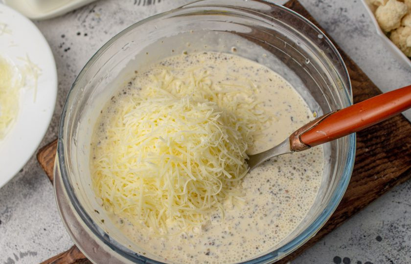 1. Этап. Запеканка из кабачков, брокколи и цветной капусты: К яично-сливочной заливке добавьте 100 грамм тертого сыра. Перемешайте.