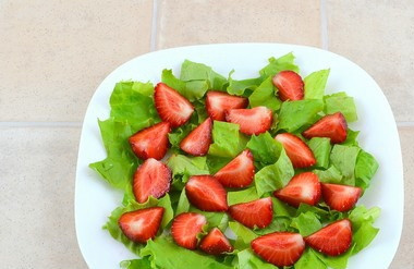 1. Этап. Салат Сердце любимого: Клубнику разрежьте на четвертинки и разложите поверх салата.