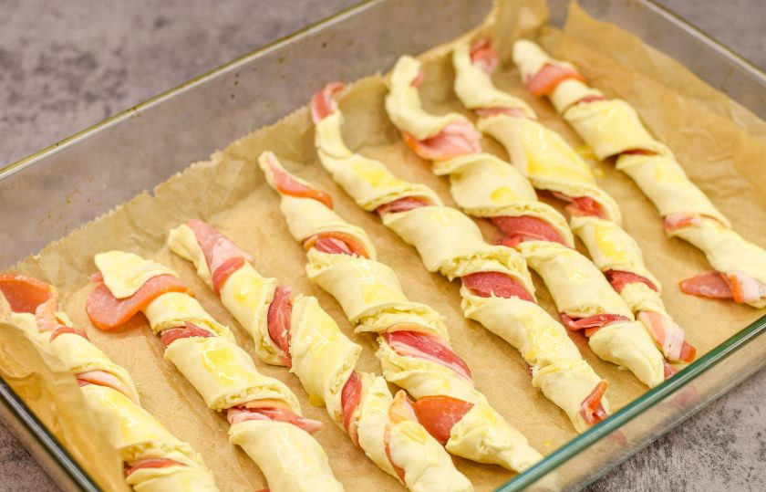 1. Этап. Слоеные палочки с сыром и беконом: Переложите заготовки на противень, застеленный пергаментом. Смажьте все слойки яйцом. После выпекайте при 180 градусах 18-20 минут.