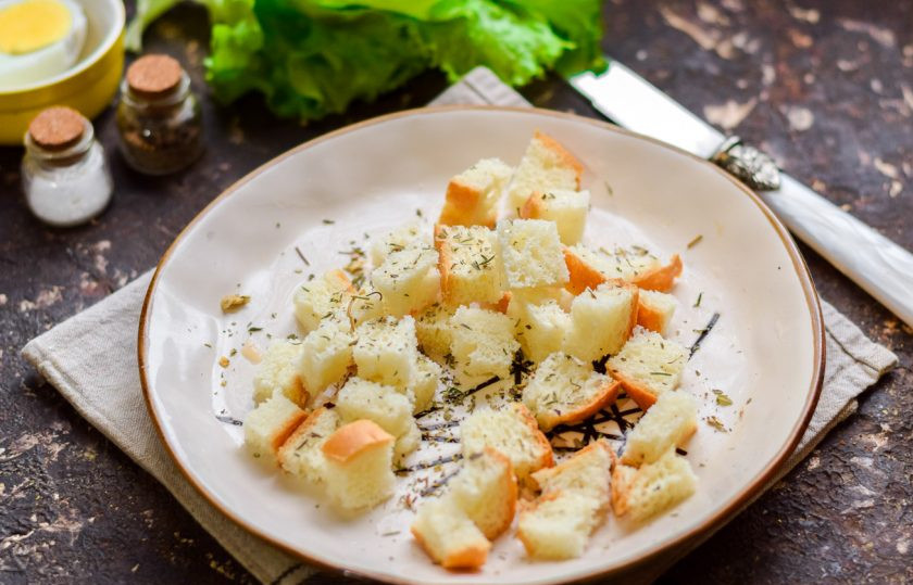 1. Этап. Салат Цезарь с индейкой: Батон нарежьте кубиками и посыпьте специями для салата 