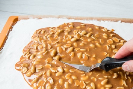 1. Этап. Сникерс в домашних условиях: Выкладываем немного остывшую карамель с орехами на застывший слой нуги, разравниваем. Отправляем в холодильник для застывания.