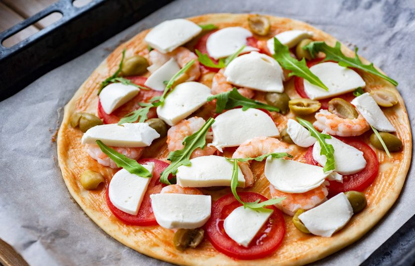 1. Этап. Пицца с оливками и креветками: Поверх разложите тонкие ломтики моцареллы и веточки рукколы. Отправьте пиццу на противне выпекаться в уже разогретую до 180 градусов духовку на 15 минут.