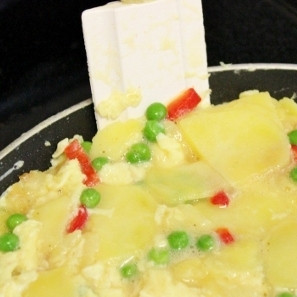 1. Этап. Испанская тортилья: 5. В сковороде разогрейте ложку масла, плиту включите на быстрый огонь. Выложите в сковороду смесь из картофеля, лука и яиц. В первую минуту жарки мешайте смесь лопаточкой, затем постарайтесь смесь выровнять. Лопаткой отделите края тортильи от сковороды.