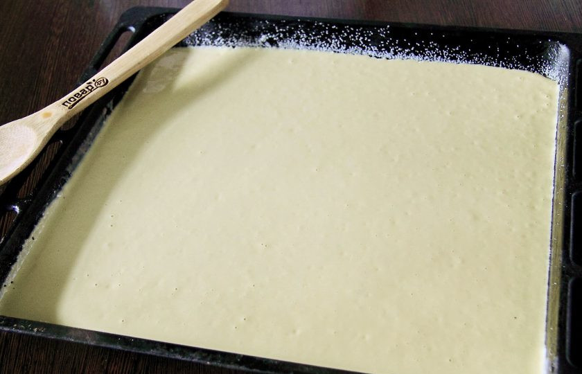 1. Этап. Заливной пирог с щавелем: Противень смажьте маслом и присыпьте дно и бока манкой. Вылейте тесто.