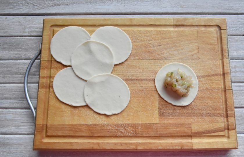 1. Этап. Момо с курицей: Отдохнувшее тесто стало более мягким и эластичным. Раскатайте его в пласт, толщиной 1-2 мм. и стаканом вырежьте из него круглые заготовки для момо. В центр каждого кружочка из теста выложите начинку.