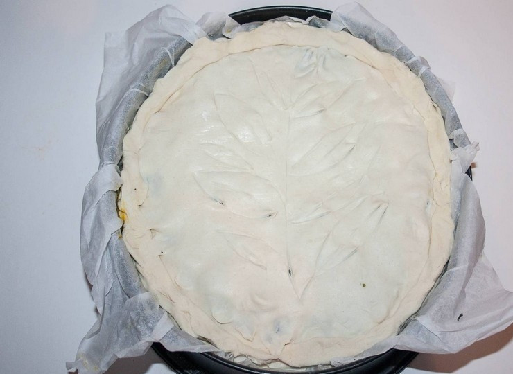 1. Этап. Пасхальный пирог со шпинатом и рикоттой: 4. Накройте пирог вторым пластом слоеного теста и закрепите края. Острым ножом нанесите узор, протыкая верхний пласт теста: так будет выходить пар при выпечке. Смажьте пирог молоком или взбитым яйцом.