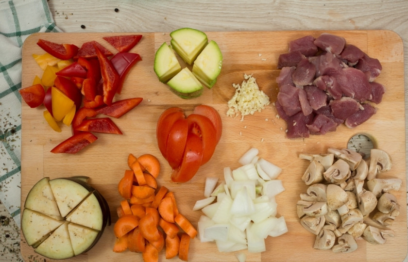 1. Этап. Овощное рагу со свининой: Все овощи советую порезать скорее крупно, чем мелко. Мясо порежьте кубиками. Баклажан и кабачок — четвертинками. Морковку, перец — ломтиками, лук — полукольцами. Чеснок только нужно мелко порубить.