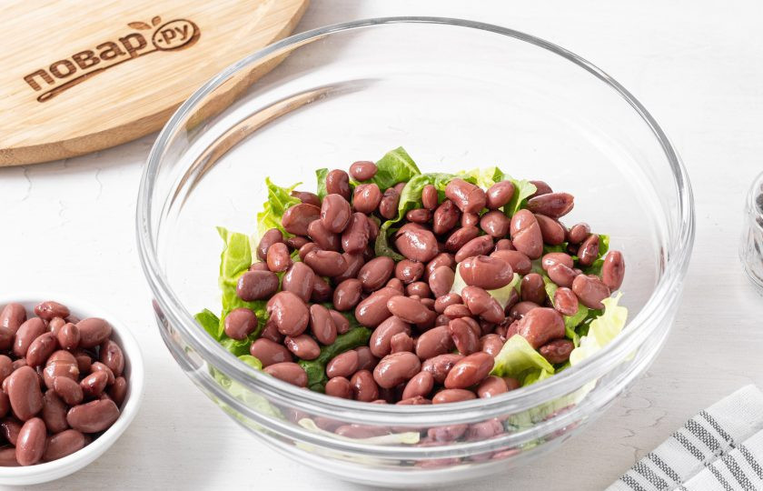 1. Этап. Салат с фасолью и ананасом: С консервированной фасоли слейте жидкость, откиньте на сито и дайте стечь воде. Переложите в миску.