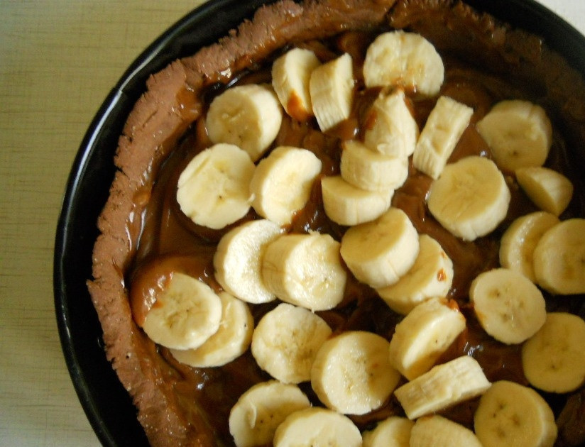 1. Этап. Шоколадно-банановый торт: Когда форма из теста выпечется, достаньте ее из духовки и остудите. Откройте банку сгущенки, вылейте ее содержимое в форму. Очистите бананы, нарежьте их кружочками. Выложите бананы на сгущенку.